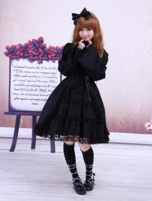 Full front view of black cotton Gothic Lolita one-piece dress on model with flower backdrop display