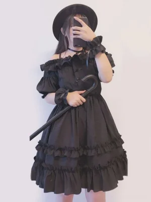 Black Gothic Lolita OP dress off-shoulder with ruffled neckline puff sleeves tiered layered ruffles front view worn by model with fedora
