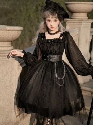 Black Gothic Lolita OP dress front three-quarter view worn by model at outdoor stone balcony, featuring ruffled square neckline, long puff sleeves, wide silver chain waist belt, and voluminous tulle skirt