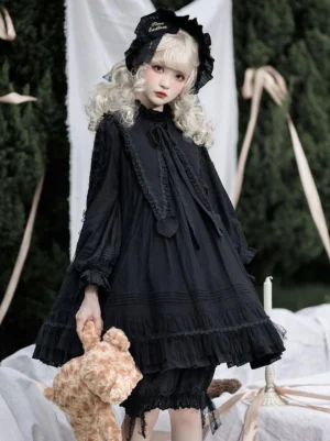 Black Gothic Lolita OP dress front view with tiered ruffles and lace collar, worn by model in garden setting