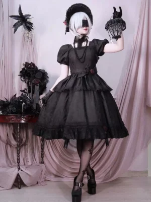 Full front view of black gothic lolita op dress on model wearing blindfold and gothic styling with birdcage prop and sheer black stockings