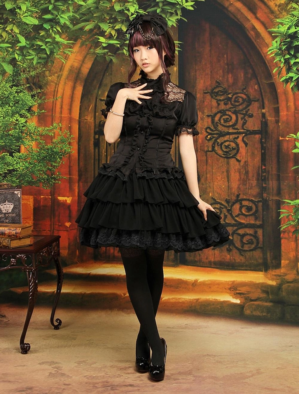 Complete black gothic lolita ensemble featuring chiffon tiered ruffle skirt with lace-collar short-sleeve blouse model front pose vintage architectural backdrop