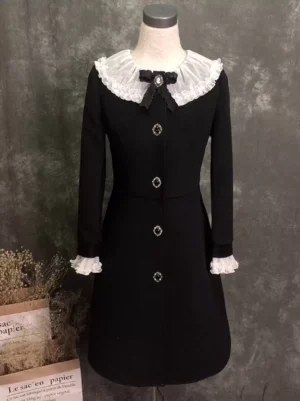 Black Gothic Lolita overcoat with white ruffled Peter Pan collar and gemstone buttons full front view on mannequin with dried flower studio backdrop