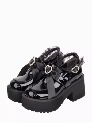 Black gothic lolita platform pumps front three-quarter view featuring glossy patent leather, pearl-embellished heart bow, rhinestone buckle, and lace ankle strap detail on white background