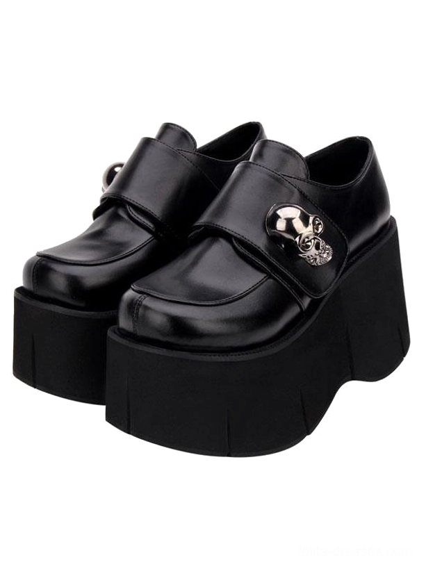 Black lolita platform shoes front-side flat lay displaying large polished skull buckle ridged flatform sole velcro strap closure and refined round toe silhouette on white background