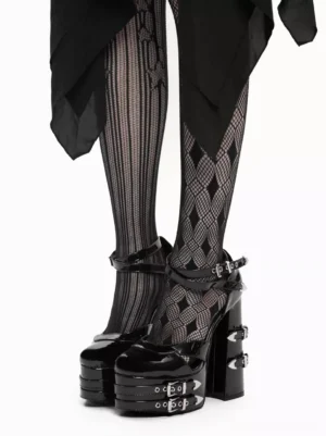 Black patent leather Lolita platform sandals with grommets front close-up view showing dual ankle buckles and multi-layer platform sole worn with striped fishnet tights and black draped skirt
