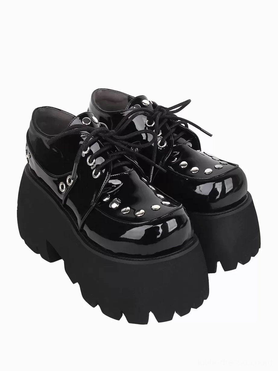 Pair of black Gothic Lolita platform shoes right three-quarter front angle displaying patent leather, silver rivets, and lace-up fastening system