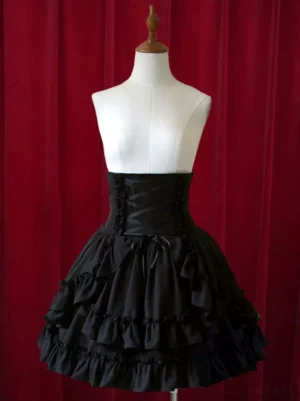 Black Gothic Lolita short skirt front view with high waist, cascading layered ruffles, ribbon corset waist detailing, worn on dress form with red velvet background, classic lolita fashion