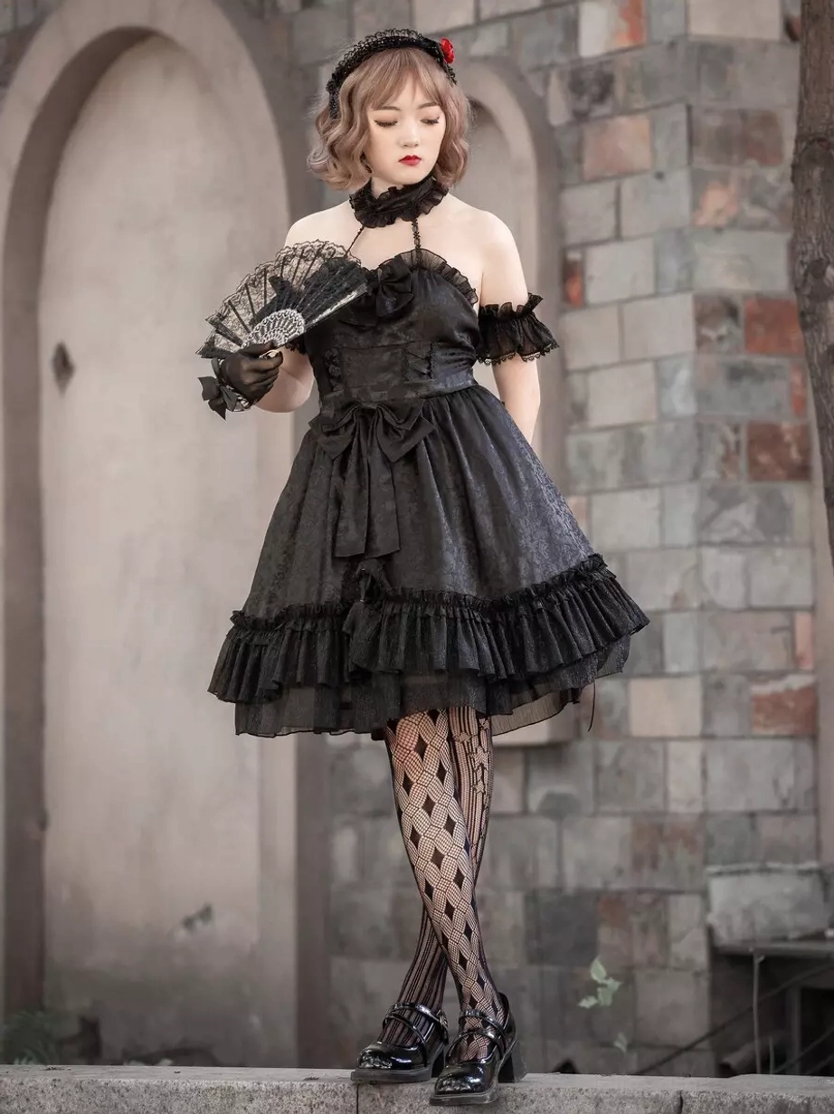 Black Gothic Lolita sleeveless dress with jacquard fabric and cascading ruffled skirt hem, featuring off-shoulder design and rose hair ornament, full front standing view