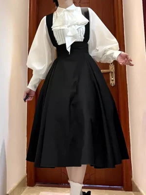 Gothic Lolita black suspender skirt worn by female model full front body view with pleated midi length black skirt and white bishop sleeve shirt featuring large ruffled neck bow