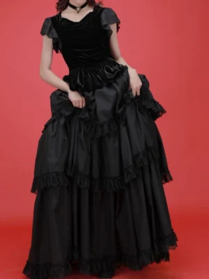 Black gothic lolita tiered dress with velvet bodice and lace layers front three-quarter view worn on model with red studio background