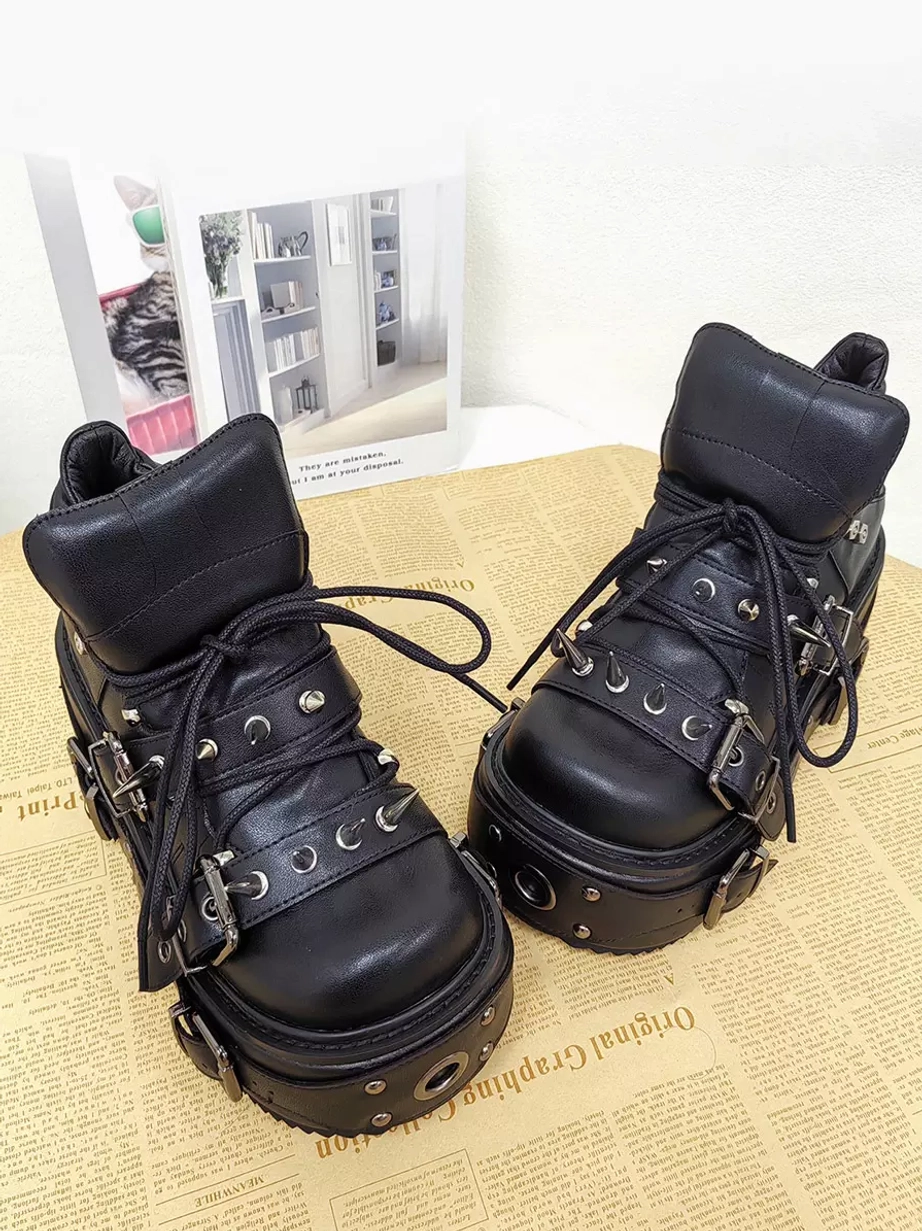Front alternative angle of black Gothic Lolita wedge boots displaying metal eyelets buckle straps and premium PU leather construction on styled background