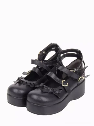 Black gothic lolita platform wedge pumps pair front three-quarter view showing matte PU leather heart-shaped gold buckles ruffled bow straps round toe
