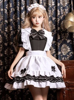 Black gothic maid lolita dress with ruffles and oversized chest bow - front full-body view on model wearing matching maid headband in vintage indoor setting
