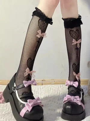 Black lolita knee-high socks with heart mesh pattern and pink bow details paired with pink Mary Jane shoes, featuring ruffled lace cuffs and romantic fishnet design