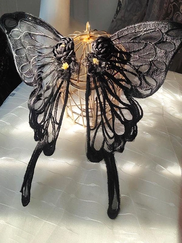 Black embroidered lace butterfly hair accessory with hollow wings and flower embellishment displayed flat with golden metal ornament - Sweet Lolita headwear front view