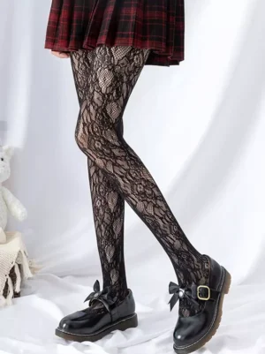Black embroidered vine lace fishnet stockings side profile leg shot featuring intricate botanical pattern with red tartan skirt