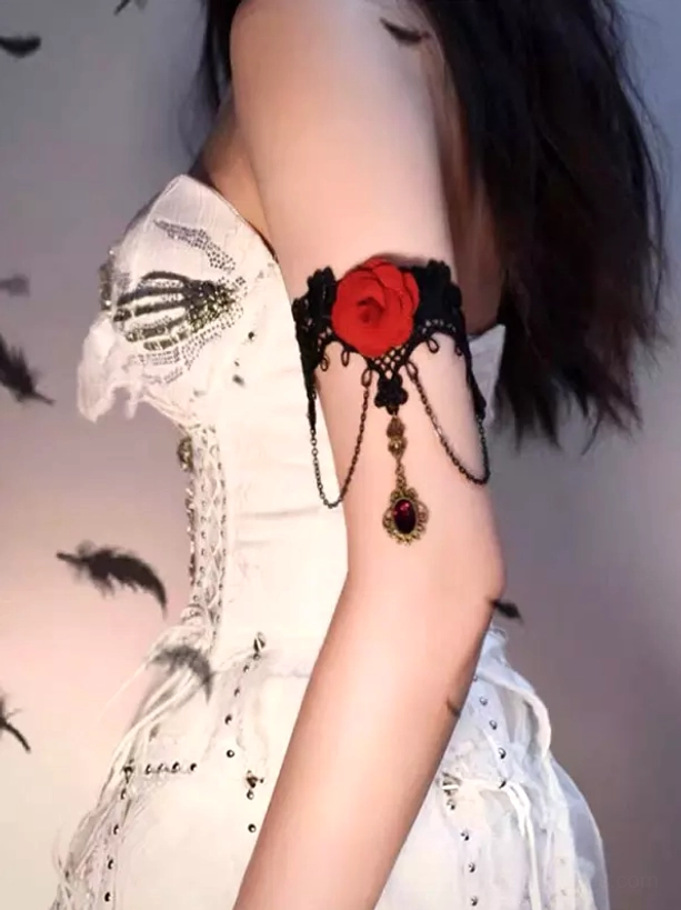 Black lace gothic lolita upper arm cuff with red fabric rose and dangling red gem chain pendant, side rear view on model wearing white vintage dress