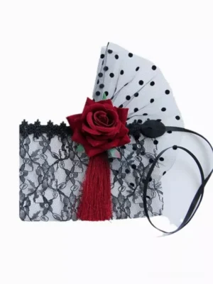 Flat lay display of black floral lace masquerade mask with polka dot mesh accents wine red rose and red tassel details