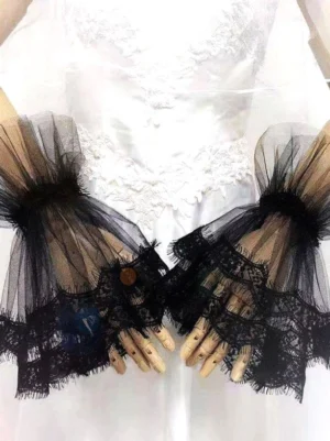 Black lace lolita wrist cuffs layered ruffle design overhead view with white wedding dress backdrop sheer tulle eyelash lace trim