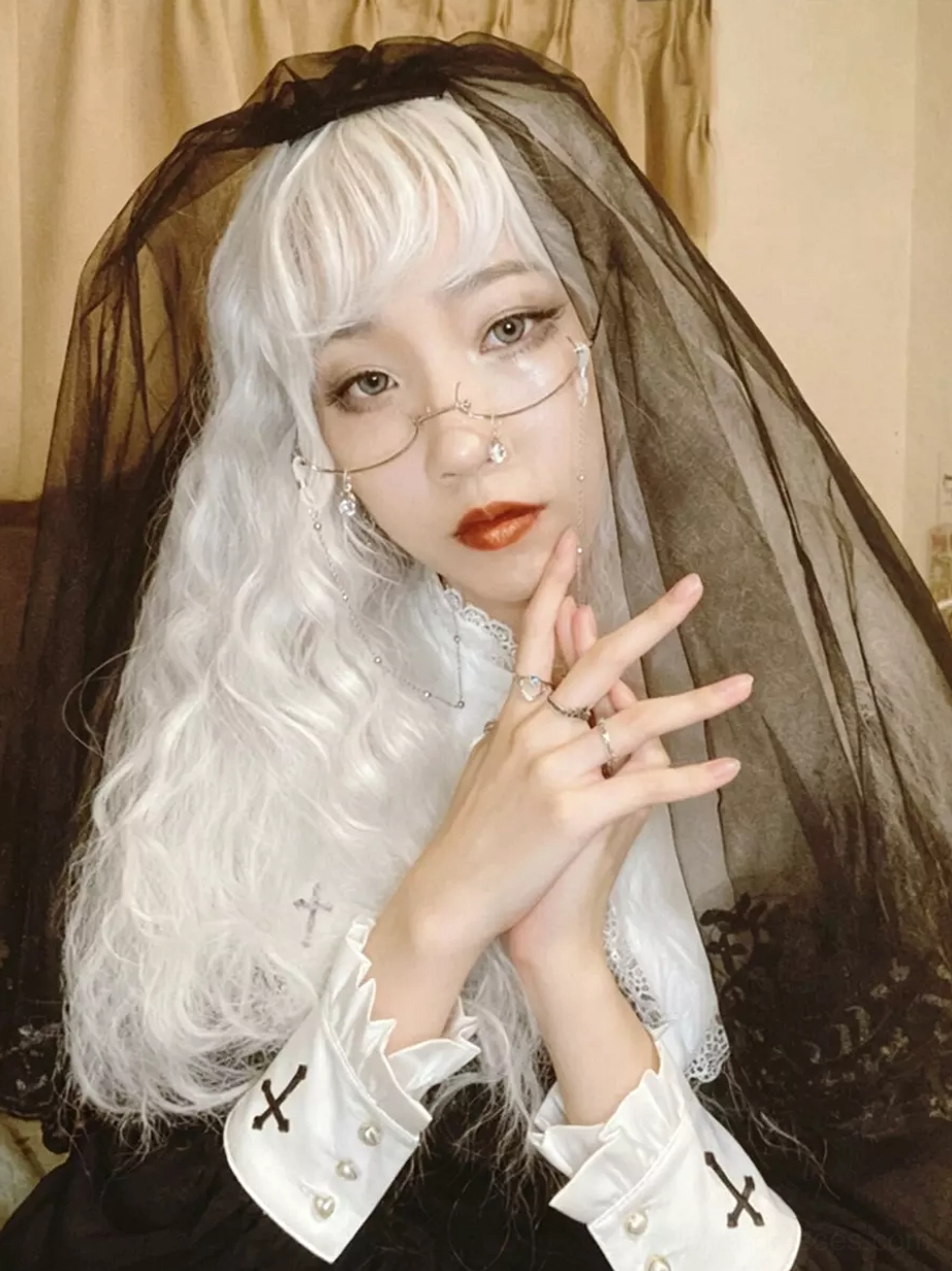 Black mesh head veil front portrait worn by model in white curly hair gothic nun-style outfit, solid black sheer fabric half-face covering with top bow fastener