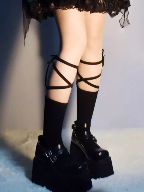 Rear three-quarter angle of black lace-up Lolita calf socks showing back cross-wrap strap design, paired with chunky platform buckle boots