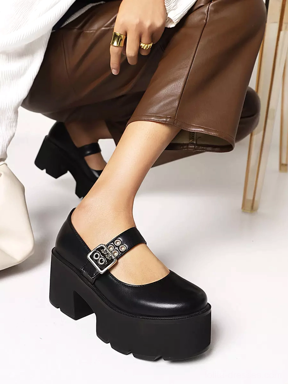 Black leather platform Mary Jane lolita shoes side view resting on gold chair frame showing smooth upper and metal buckle strap detail