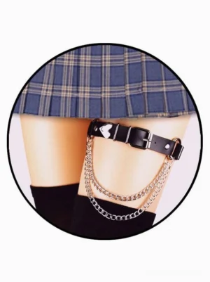 Black leather chain thigh garter with heart charm worn on model's thigh with plaid skirt and black stockings, showcasing double silver chains and romantic Lolita aesthetic