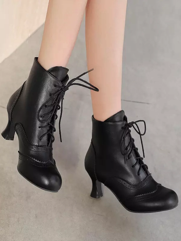 Black Lolita ankle boots displayed from side and rear angle on female legs, featuring curved heel, decorative brogue details, and authentic vintage character perfect for Lolita coordinates on plain background