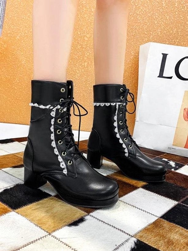 Black lace-up Lolita ankle boots with round toe and block heel decorated with white floral lace trim on checkered floor with shopping bag