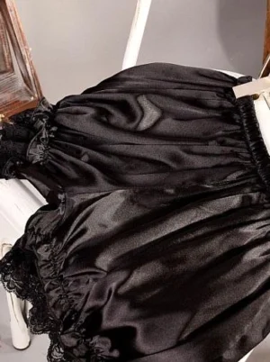 Black lolita bloomers overhead view displaying shiny silk-like fabric, black lace trim details, and full gathered silhouette for classic and gothic lolita aesthetics