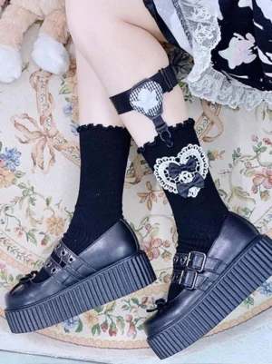 Black ribbed lolita socks with ruffled cuff and heart lace bow decoration on leg garter, styled with cute plush toy on floral carpet background