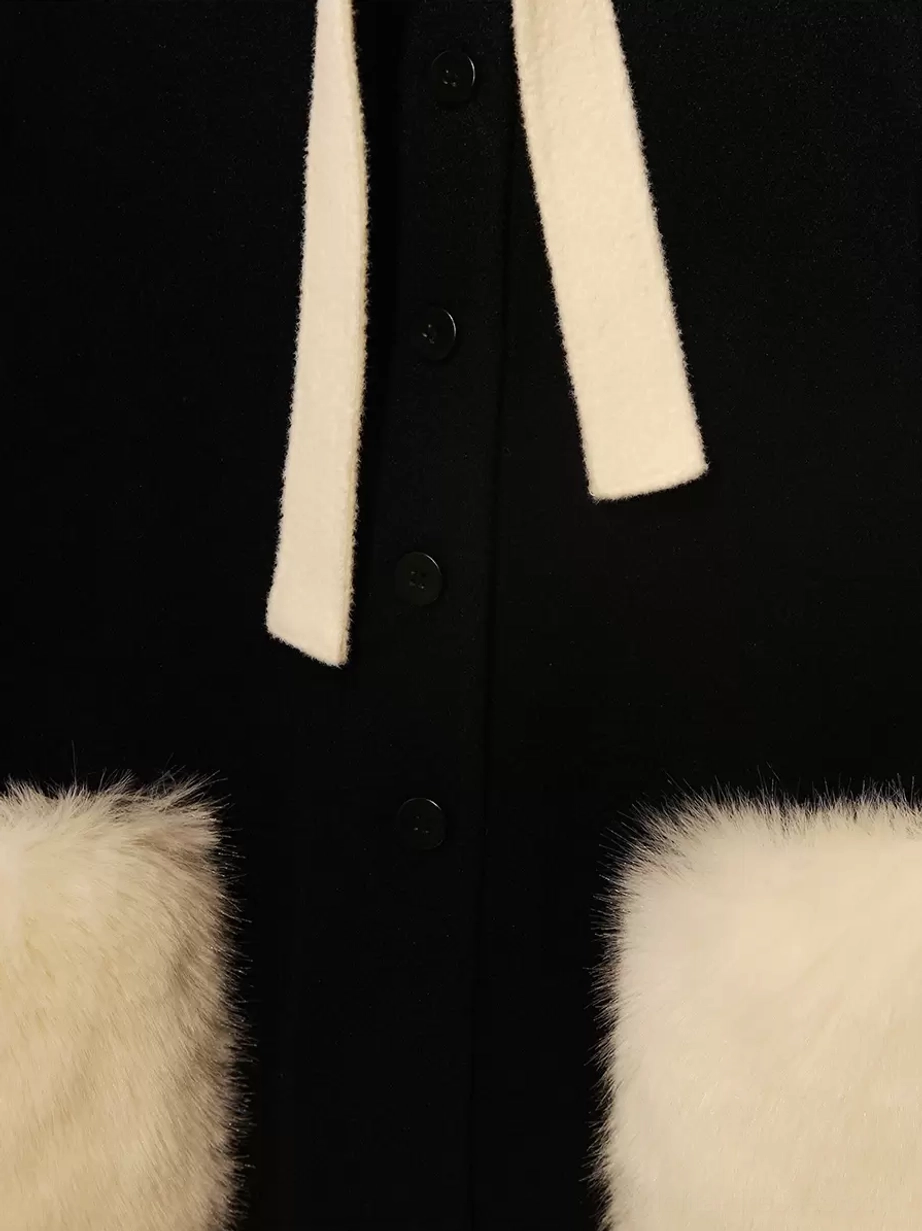Partial close-up detail of black lolita cape coat white bow strap and fuzzy square pocket with front buttons