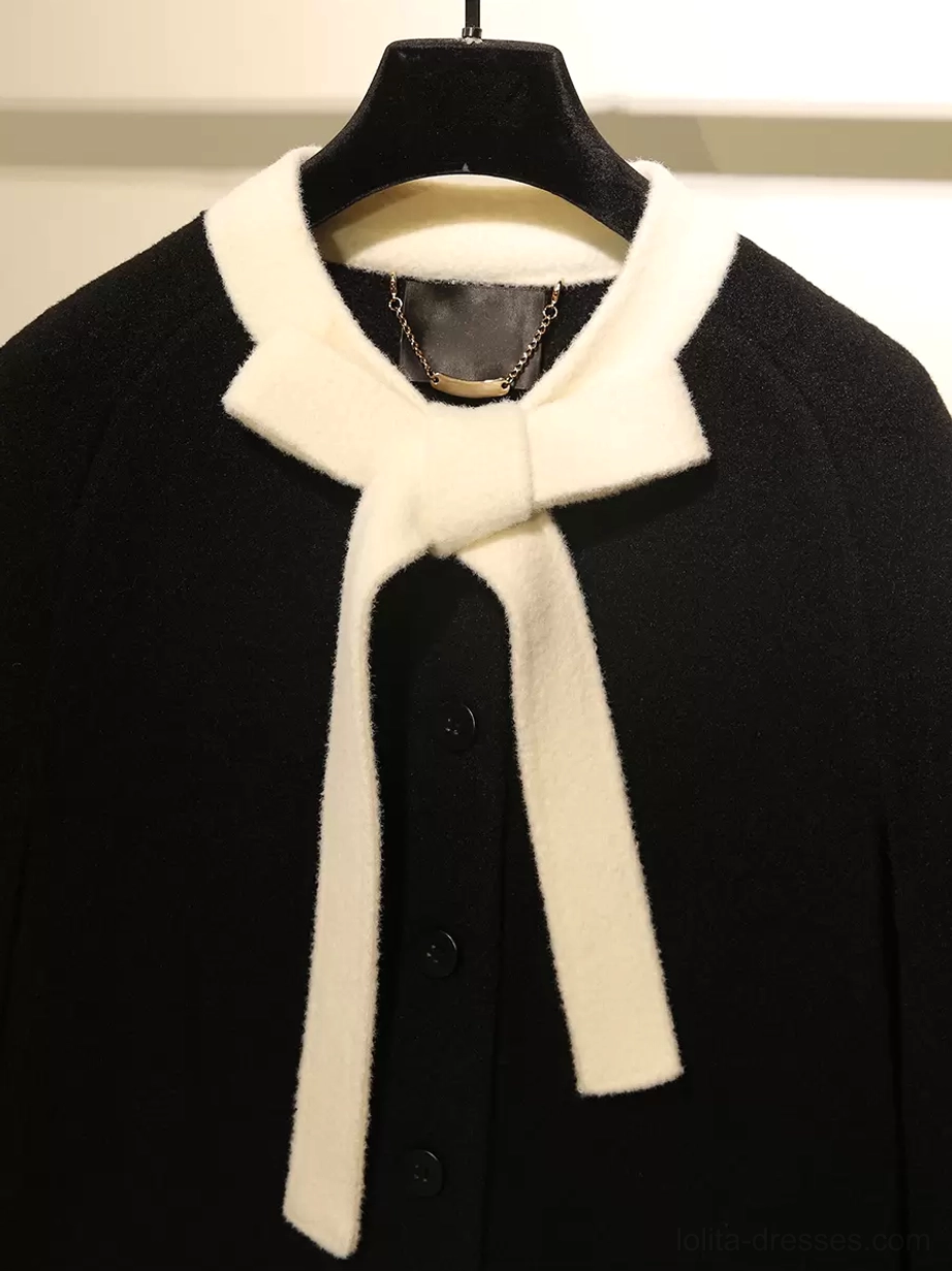 Close-up detail of black lolita cape coat white fuzzy bow stand collar with front button fastenings
