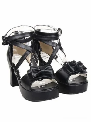 Black lolita sandals three-quarter side view showing scalloped shoe trim, cross ankle strap fastening, and decorative bow on peep toe design
