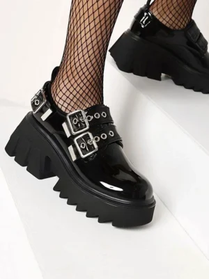 Close-up side profile of black Lolita platform shoes showing glossy patent leather finish adjustable buckle straps and serrated platform sole detail