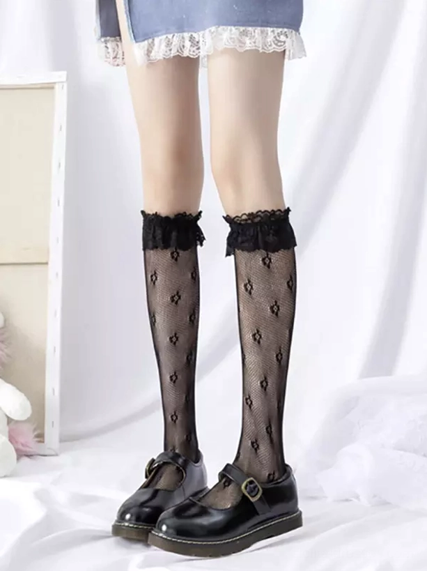 Black lace ruffle diamond jacquard fishnet knee-high socks with ruffled cuff worn with Mary Jane shoes on white studio backdrop front view