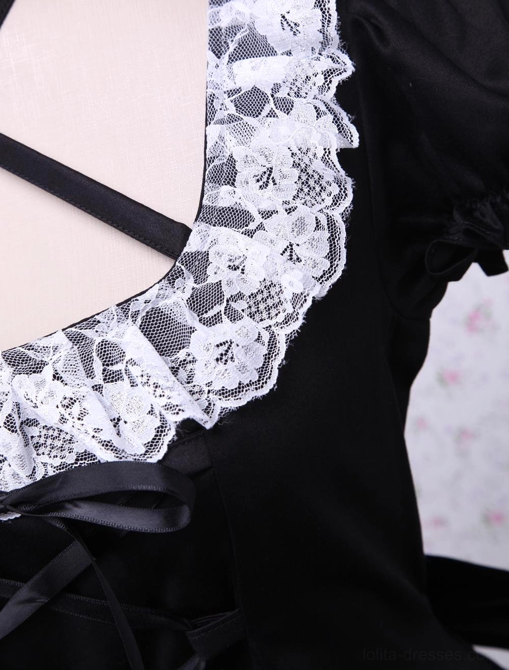 Close-up detail of lolita dress neckline and strap showing scalloped white lace trim edge and cross black satin halter strap construction