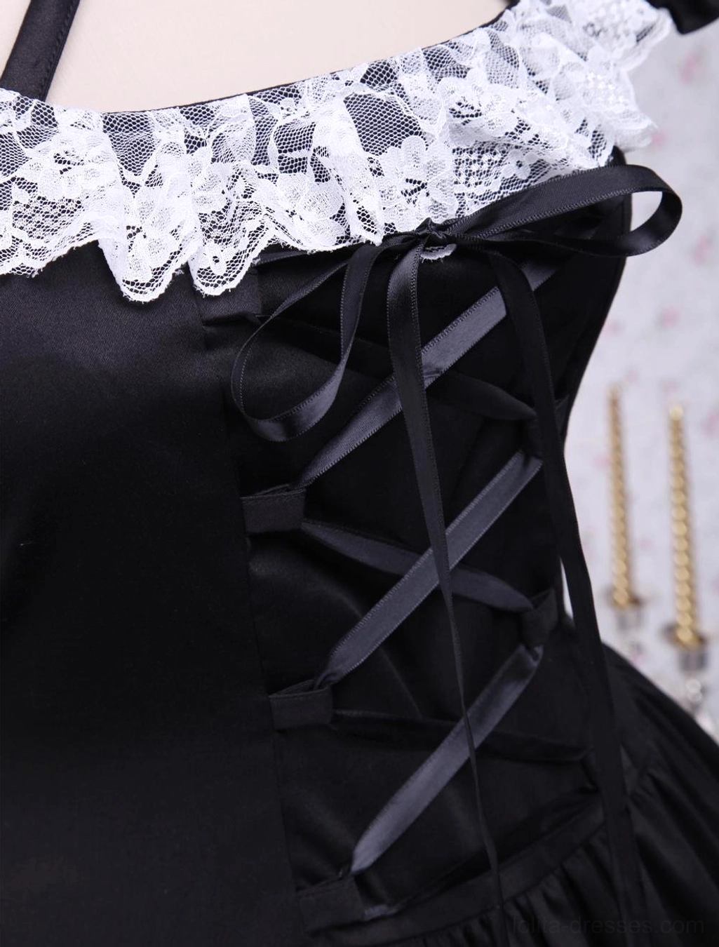Close-up detail of black lolita dress front featuring white scalloped lace collar, satin lace-up corset-style closure, and ornamental embellishments
