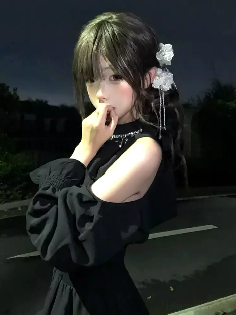 Close-up detail of rhinestone tassel neckline and lantern sleeve on black classic lolita dress, upper body side angle with flower hair accessories