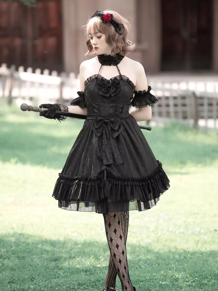 Black sleeveless lolita dress front-side angle with waist bow decoration and ruffled skirt hem, striped pattern stockings detail