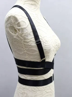Black body harness bustier left side view showing adjustable shoulder strap and layered waist bands on dress form