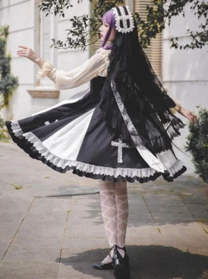 Black classic lolita sleeveless dress back and side view on model displaying adjustable shoulder straps, elastic waist, and flounced lace hem with ruffled detailing in outdoor setting