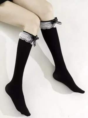 Black lolita knee-high socks with white scalloped lace cuff and black satin bow, side view on female legs