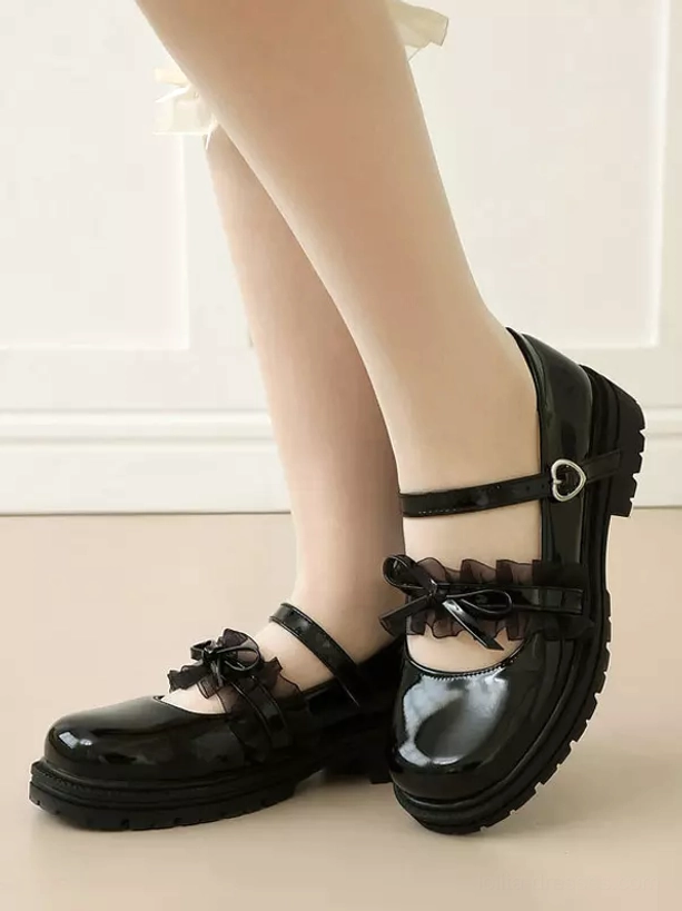 Black glossy lolita mary jane shoes side view worn on bare feet, featuring lace bow decoration and heart-shaped buckle strap with platform sole