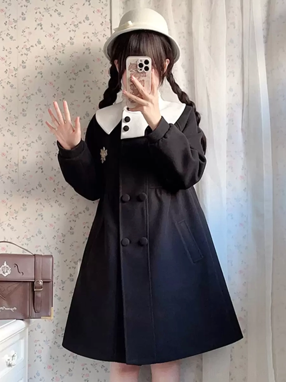 Black Rococo lolita coat front view with small side pockets and snowflake brooch accessory, contrast collar, worn with beige bucket hat