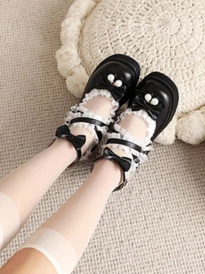 Black Lolita platform pumps top-down side view showing ankle bow straps and pearl toe accents with half-length nude hosiery on plush fabric background
