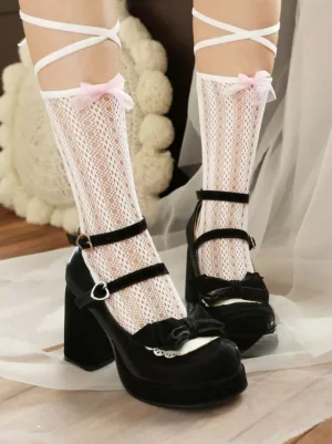 Black lolita chunky heel pumps front view worn with pink-trimmed lace socks showing cross wrap straps and bow ornament