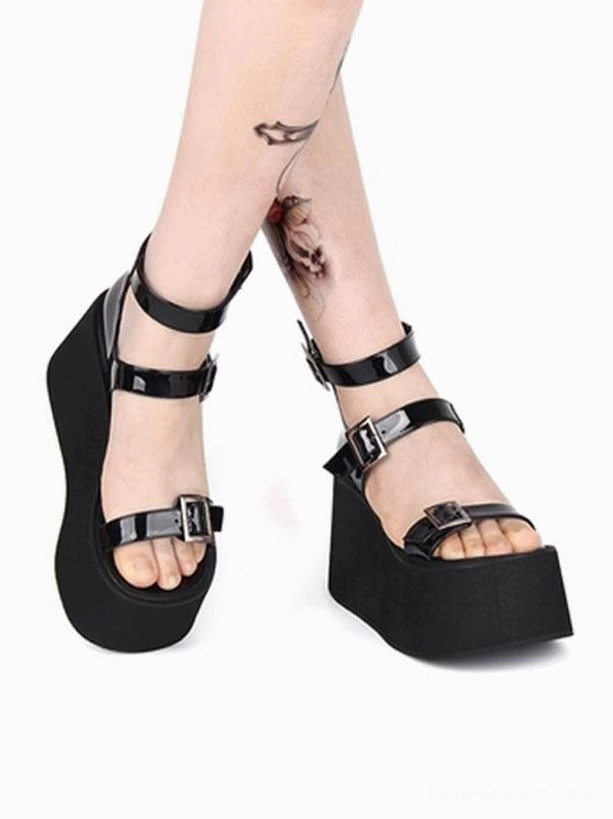 Black platform sandals side profile on model legs displaying ankle and toe buckle straps, thick platform sole, shiny patent PU upper surface, lolita fashion footwear styling