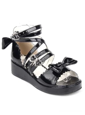 Black lolita wedge sandal right side three-quarter view showing scalloped insole heart buckle strap and rear bow decoration